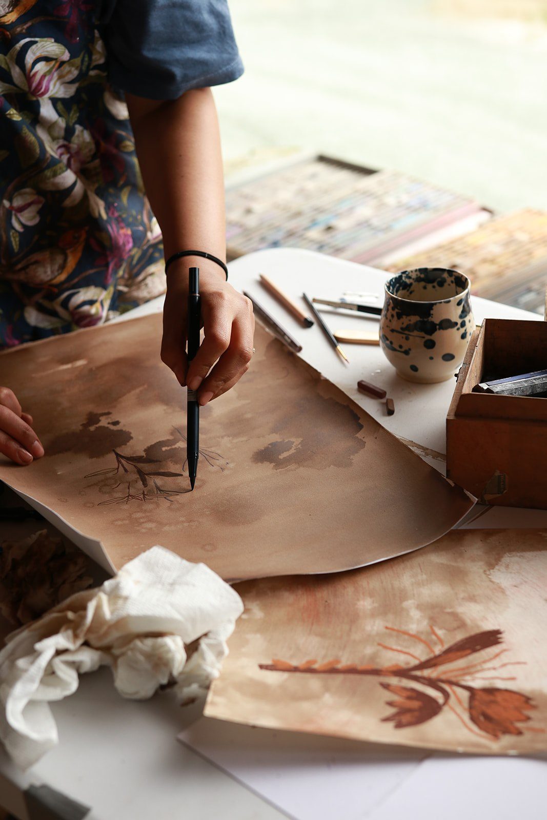 A hand drawing a botanical ink illustration at Camp Denman